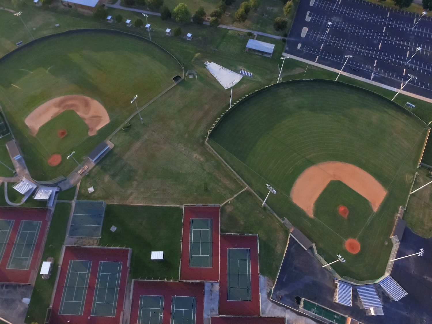 Aerial outdoor tennis court in an athletic complex at Houston, Texas, USA at sunset. Available are baseball fields and parking lots. Urban community athletics program and recreation concept.