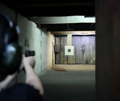Person aiming at a target in an indoor shooting range, highlighting the need for efficient gun club membership software to manage member access, scheduling, and perks seamlessly.