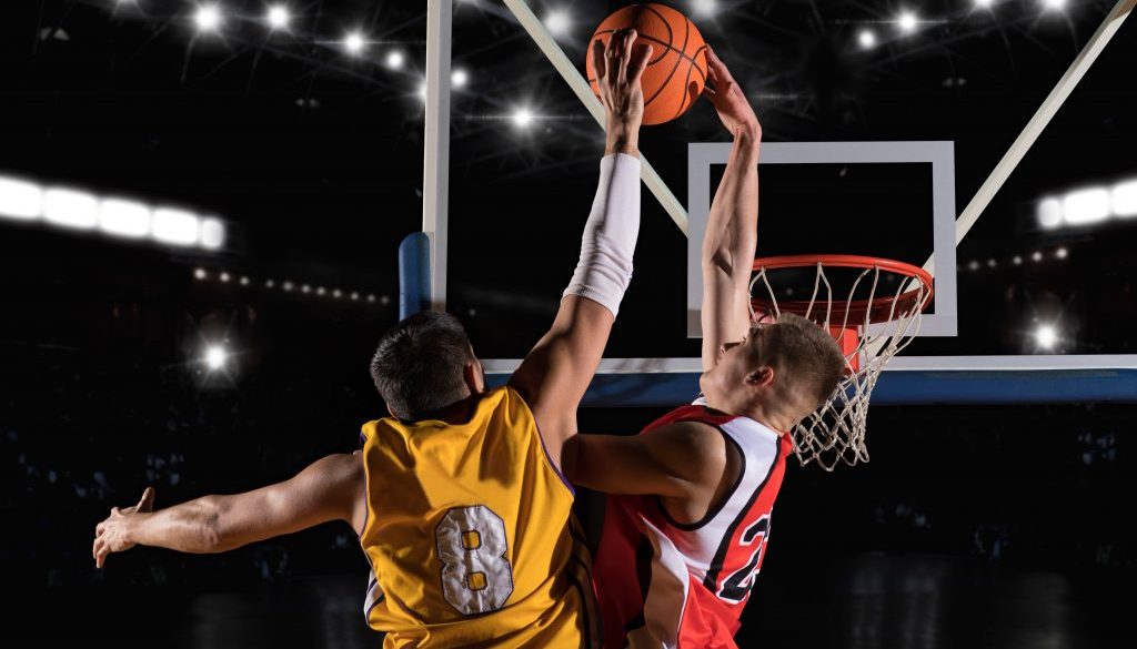 Two basketball players battle at the hoop, one going for a dunk while the other tries to block the shot. With the right basketball team management software, coaches can streamline scheduling, track payments, and keep teams like this organized for game day.
