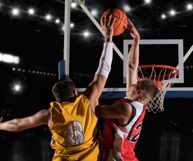 Two basketball players in arena. Blocked shot Two basketball players battle at the hoop, one going for a dunk while the other tries to block the shot. With the right basketball team management software, coaches can streamline scheduling, track payments, and keep teams like this organized for game day.