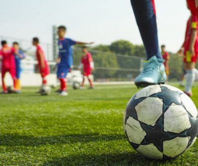 children playing soccer Youth soccer players practicing on a field with a close-up of a soccer ball in the foreground, representing organized training sessions managed efficiently with soccer club management software.