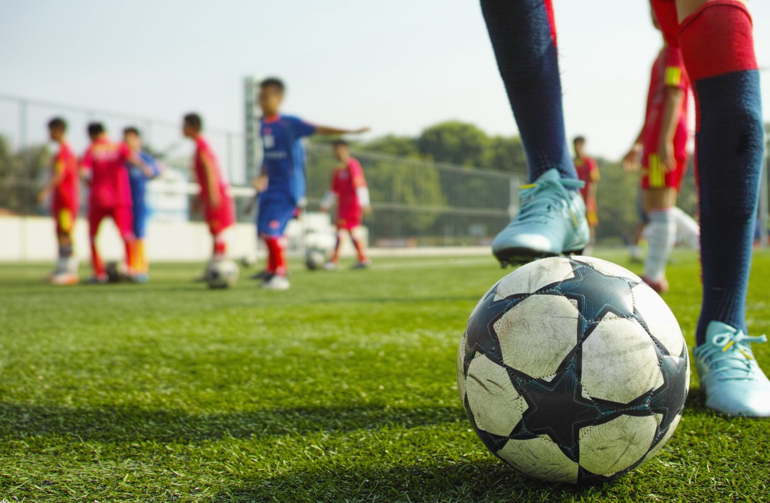 children playing soccer Youth soccer players practicing on a field with a close-up of a soccer ball in the foreground, representing organized training sessions managed efficiently with soccer club management software.