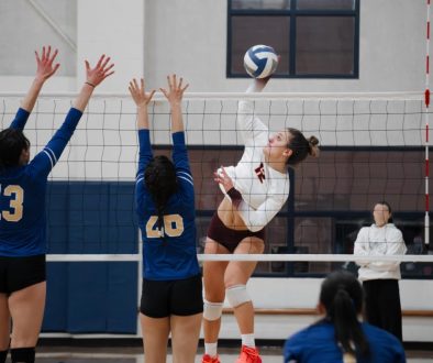 Volleyball outside hitter against a double block Female volleyball players in action at the net during a game, highlighting the need for organized scheduling and payments through volleyball club management software.