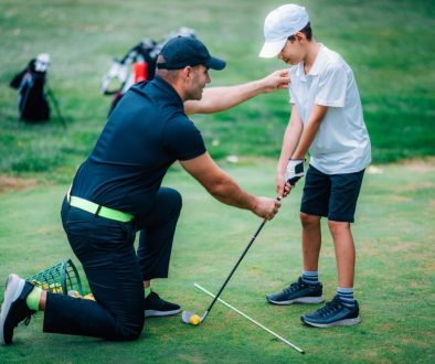 Golf Lessons. Golf instructor giving game lesson to a young boy. Golf instructor teaching a young student during a private lesson, showcasing the need for flexible scheduling on the go with golf lesson booking software.