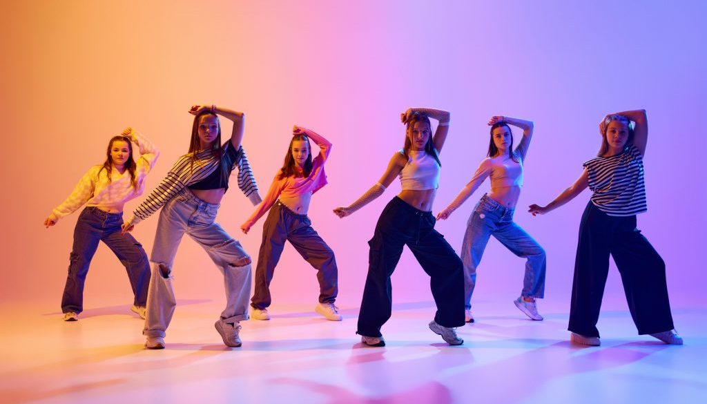 Group of active people, talented dancing hip hop against gradient studio background in neon light. Contemp