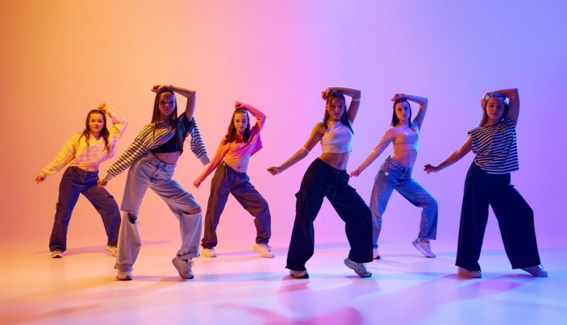 Group of active people, talented dancing hip hop against gradient studio background in neon light. Contemp