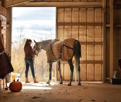 Teenage girl standing with horse in stable