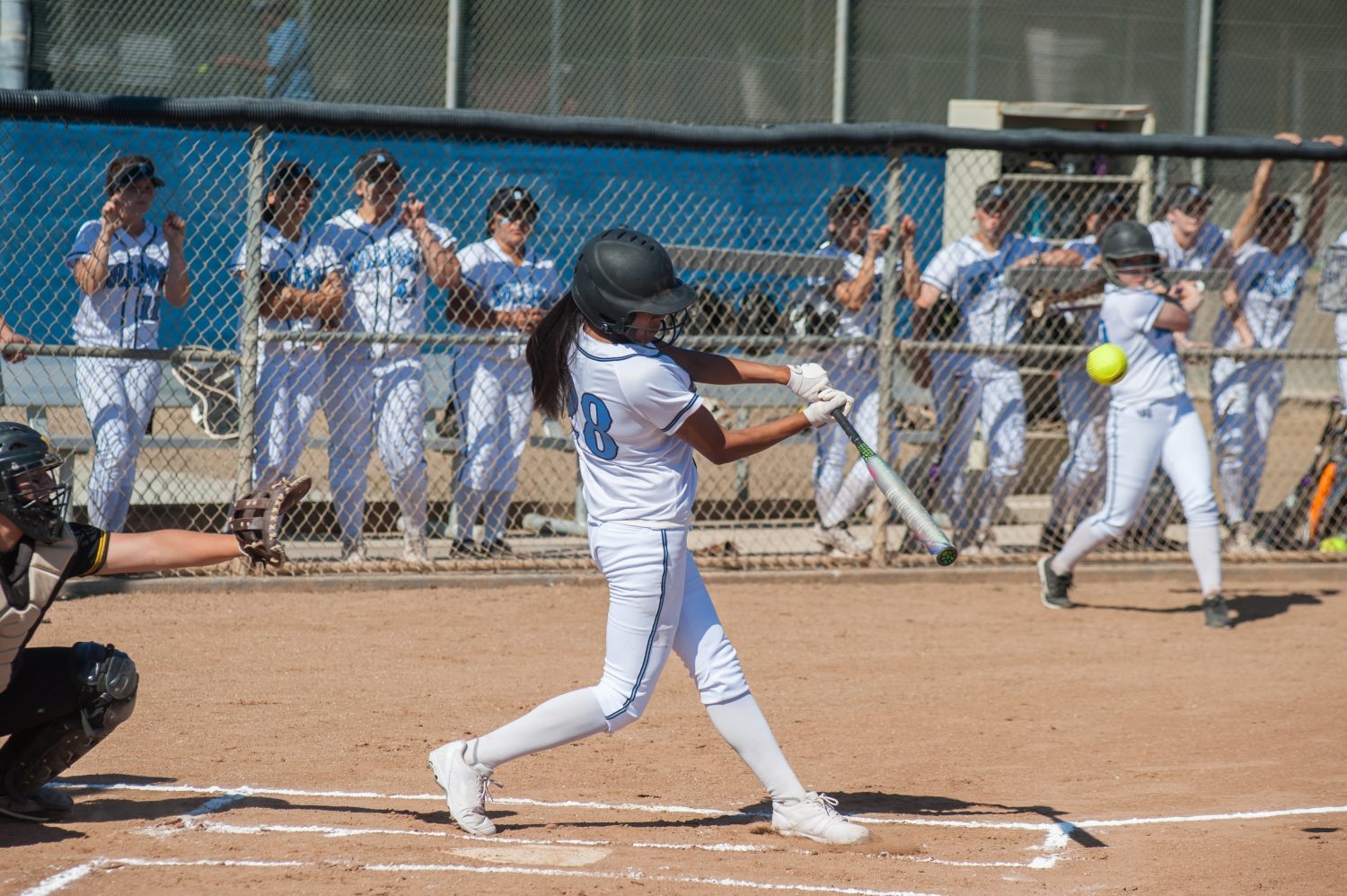 Filipino softball batter hitting a line drive during a game, representing softball team management software and player development.